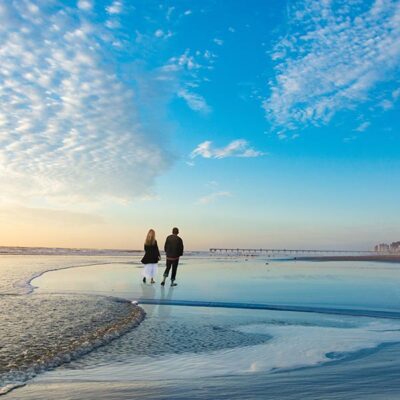 man and woman walking on Jacksonville Beach at sunset